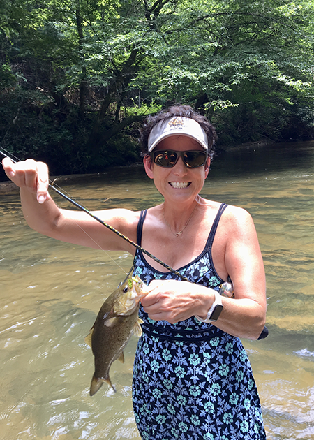 Woman holds up smallmouth bass caught on the Mitchell River in North Carolina